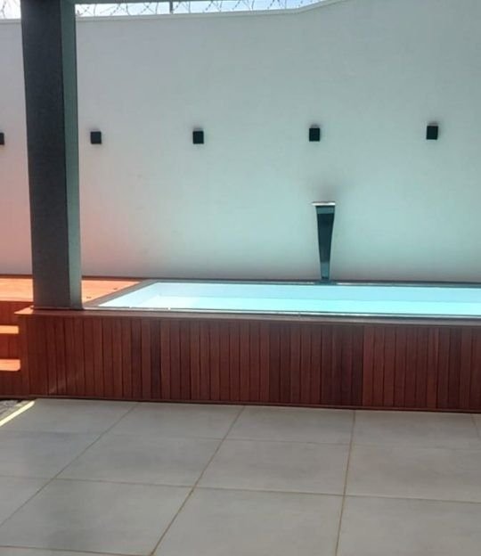 Piscina em área gourmet com iluminação noturna